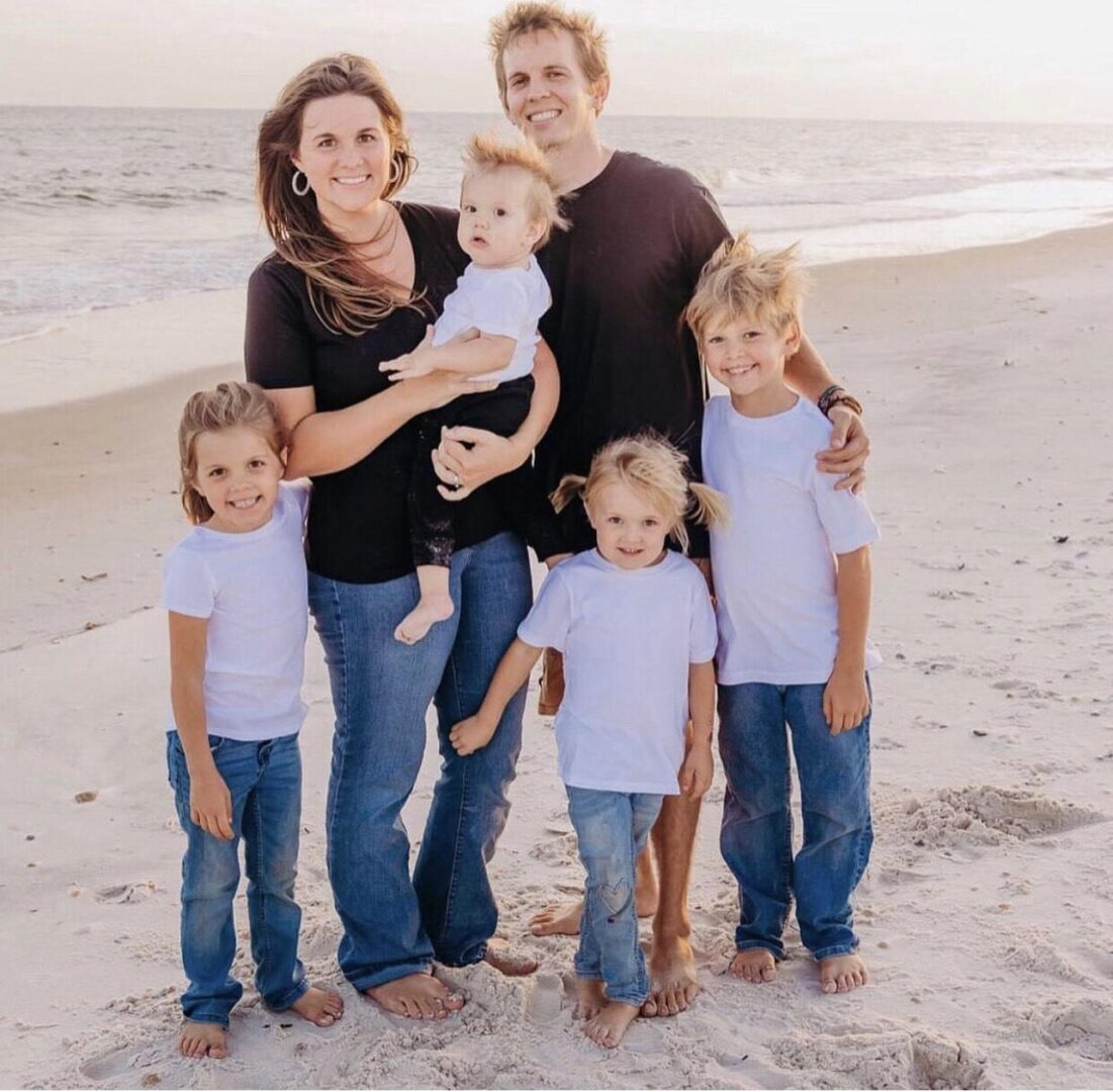 Smiling family of six on sandy beach