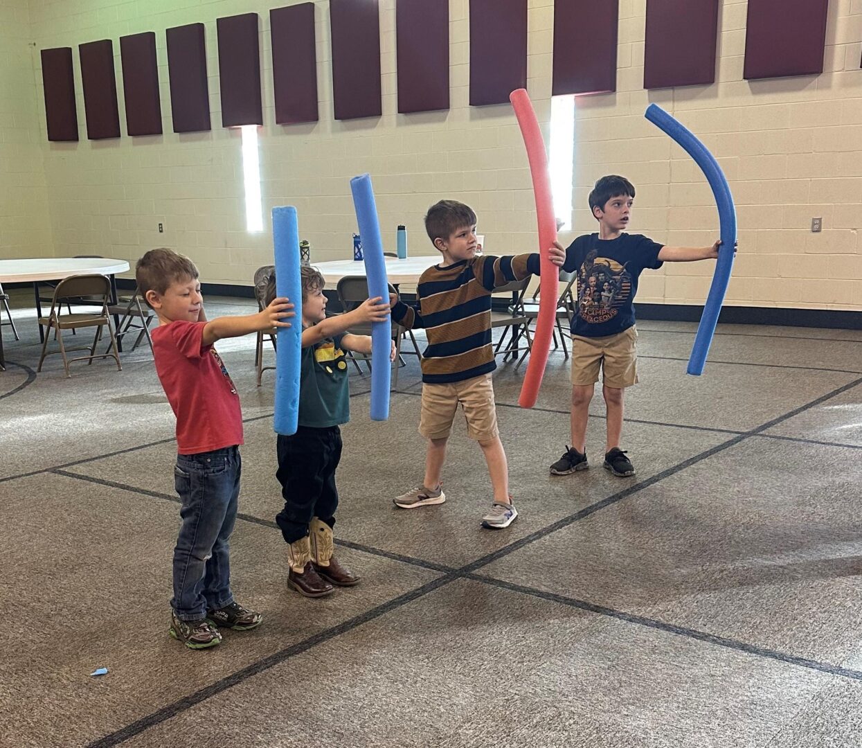 Four boys holding pool noodles like swords Four boys holding pool noodles like swords