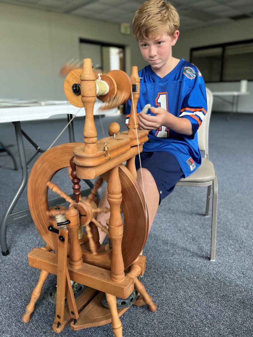 Young boy spinning yarn on wooden spinning wheel Young boy spinning yarn on wooden spinning wheel