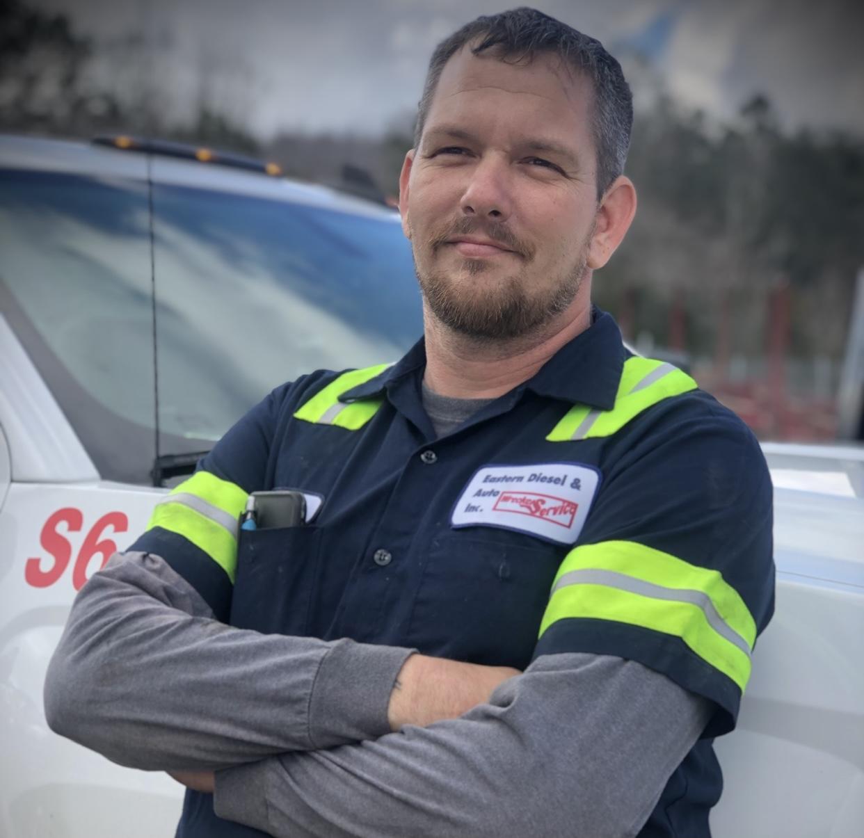 Service technician with arms crossed by truck Service technician with arms crossed by truck