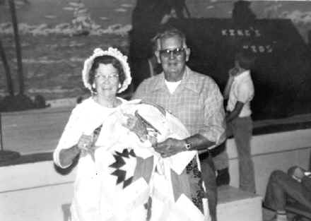 A man and woman holding flags in front of an ocean.