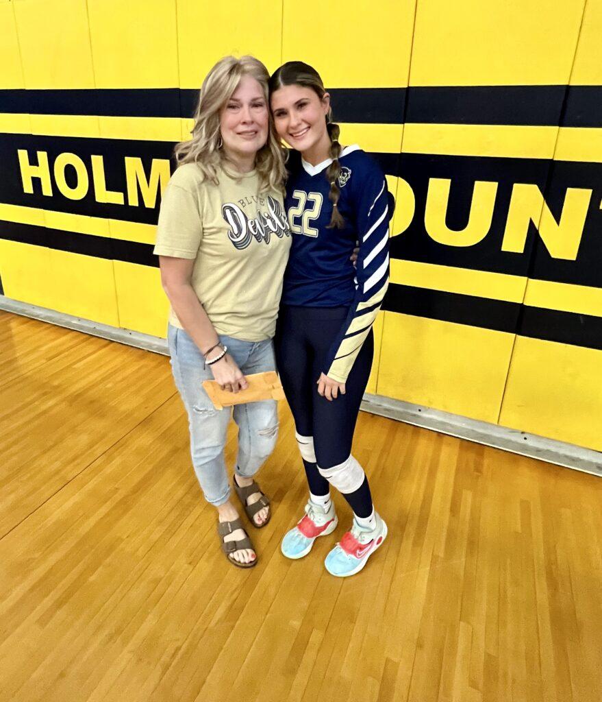 Two girls standing next to each other in a gym.