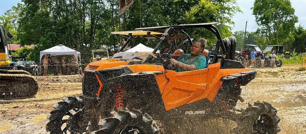 A man driving an orange utility vehicle.