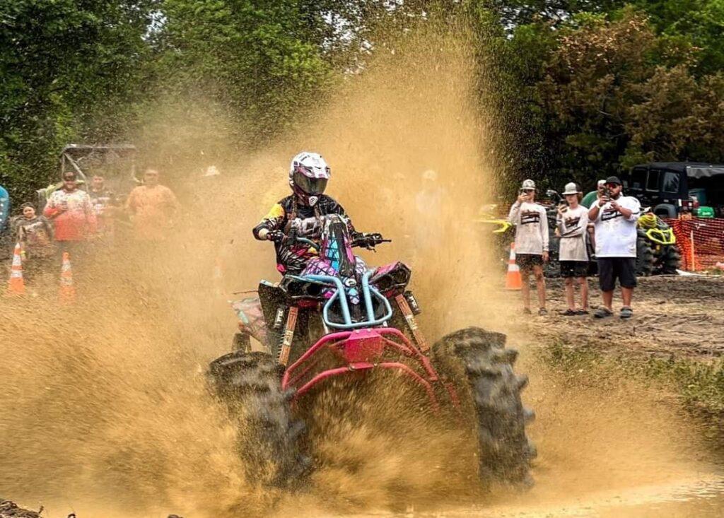 A person on a red and white atv in the dirt.