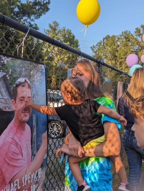 A woman holding her baby in front of a picture.