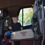 A young boy sitting in the back of a fire truck.