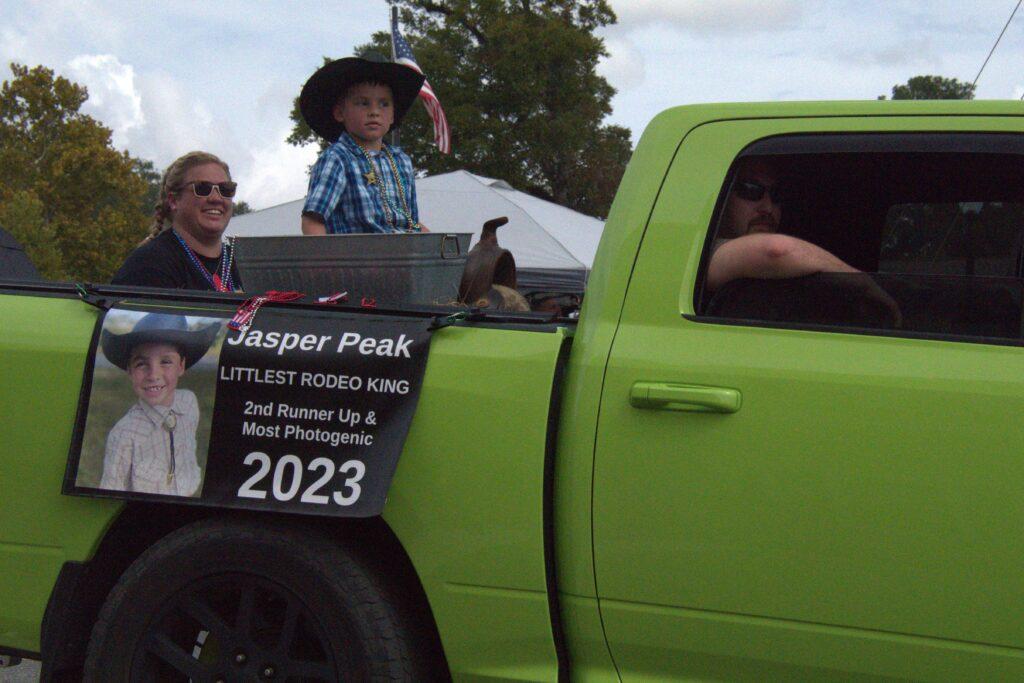 A green truck with people in the back of it.