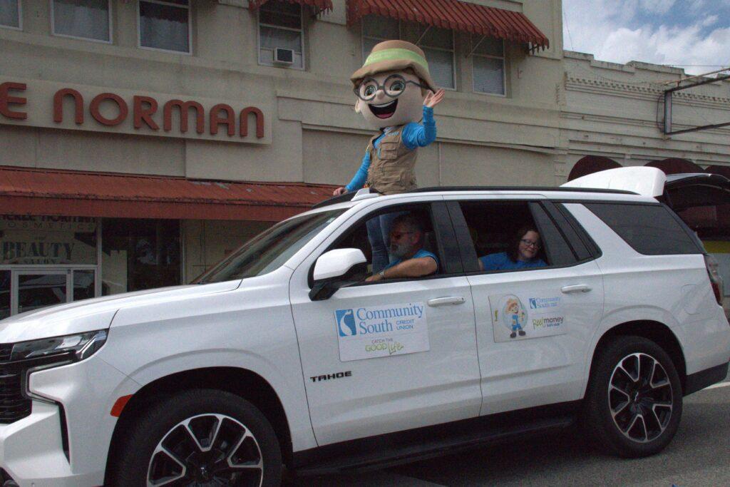 A person in the back of a car with a large head.