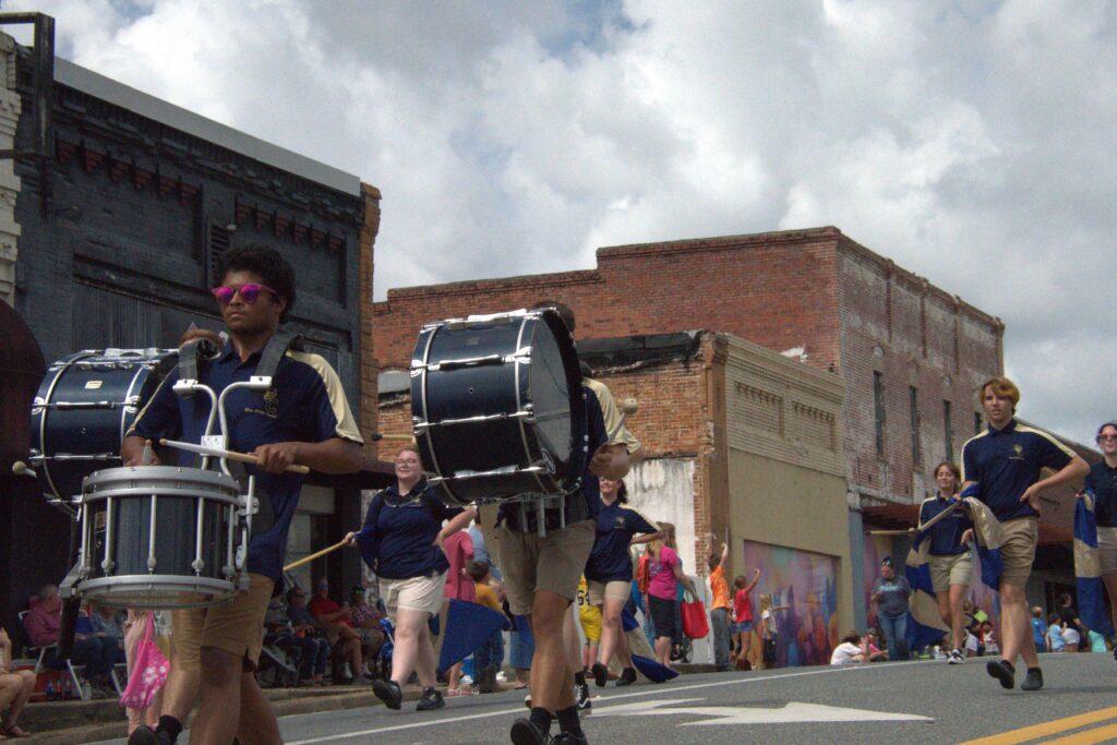 A man walking down the street with a drum.