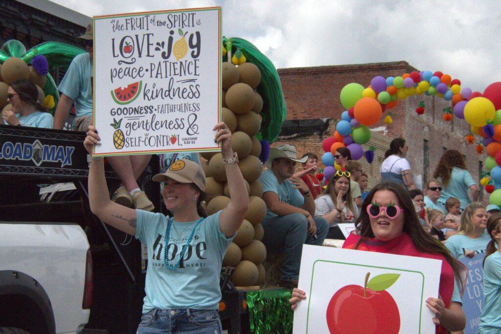 A woman holding up a sign with apples on it.