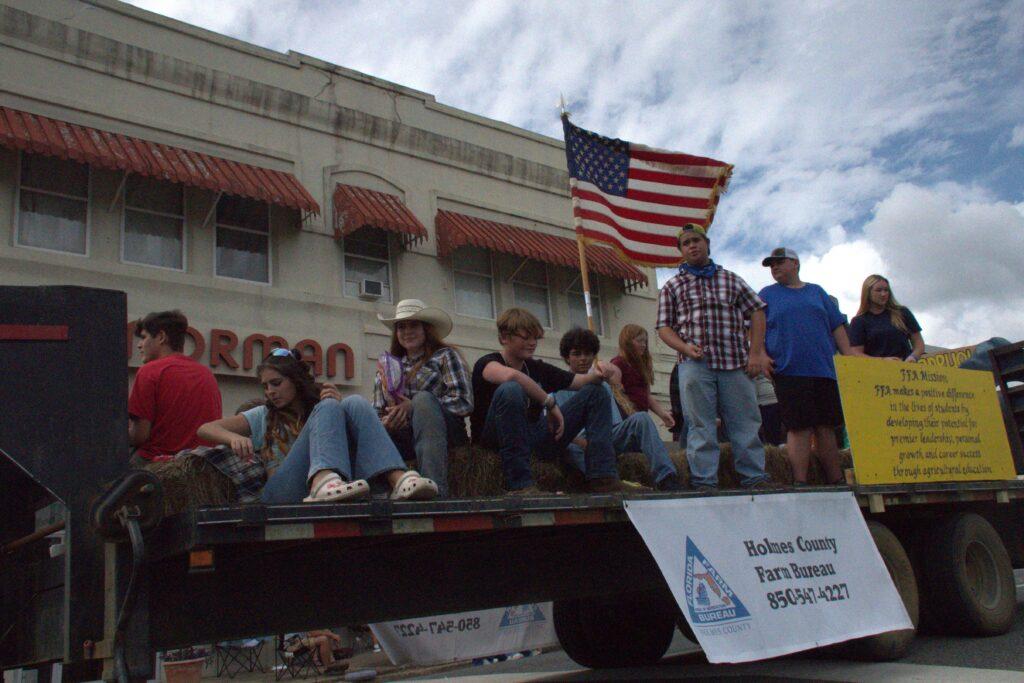 A group of people sitting on the back of a truck.