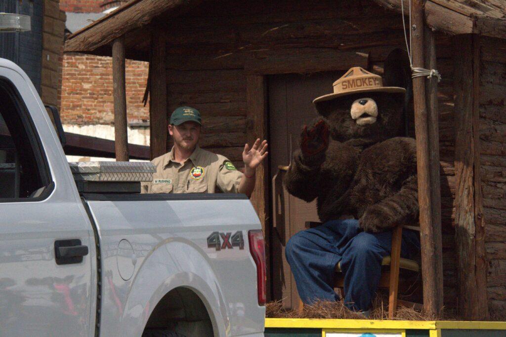 A man in a bear costume sitting on the back of a truck.