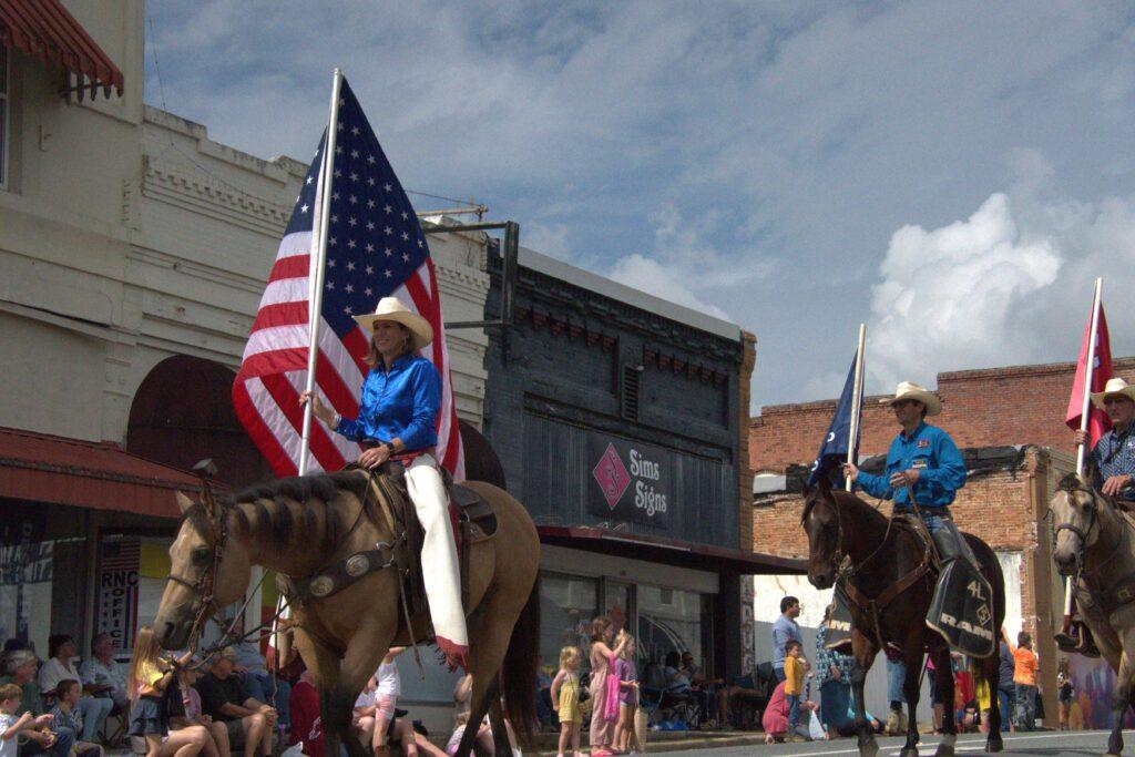 A man riding on the back of a horse holding an american flag.