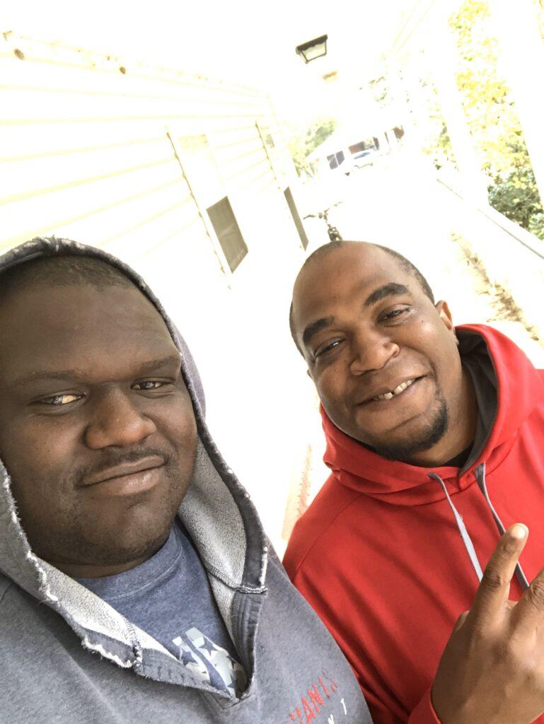 Two men standing next to each other on a porch.