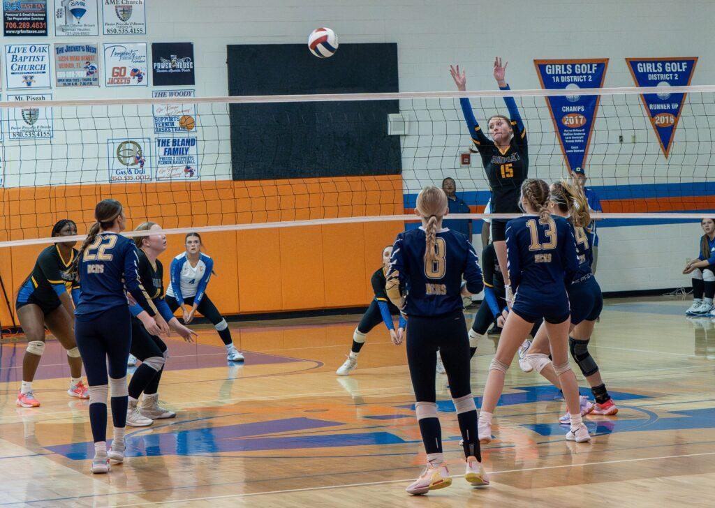 A group of people playing volleyball on an indoor court.