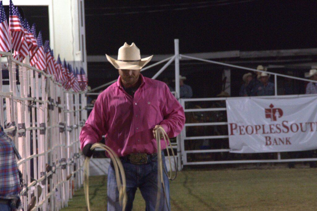 A man in pink shirt holding two ropes.