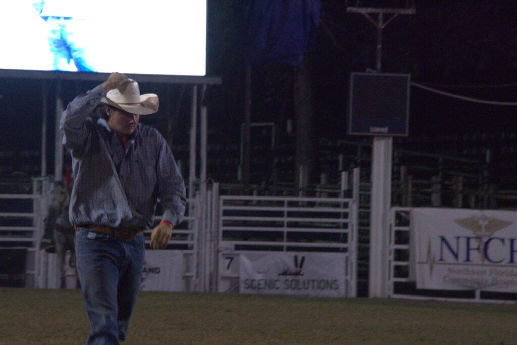 A man in cowboy hat walking across the field.