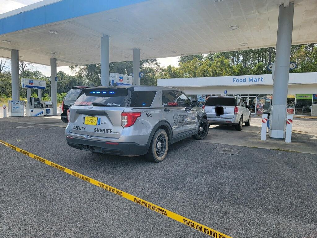 A car parked at the gas station with police tape around it.