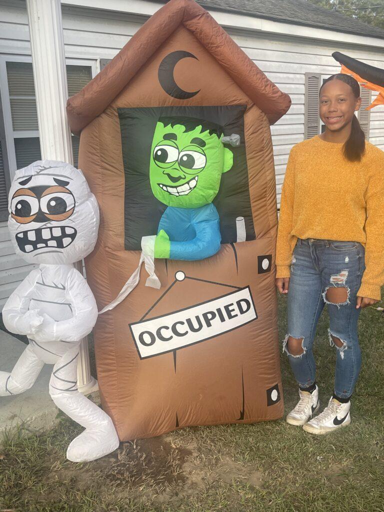 A woman standing next to an inflatable halloween decoration.
