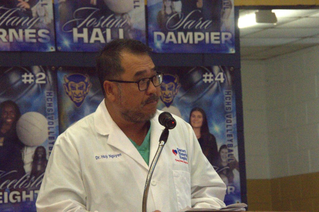 A man in white lab coat speaking at podium.