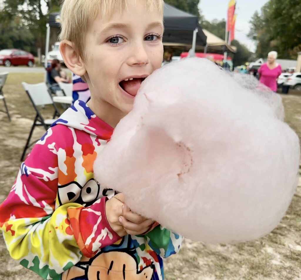 A boy is eating cotton candy outside