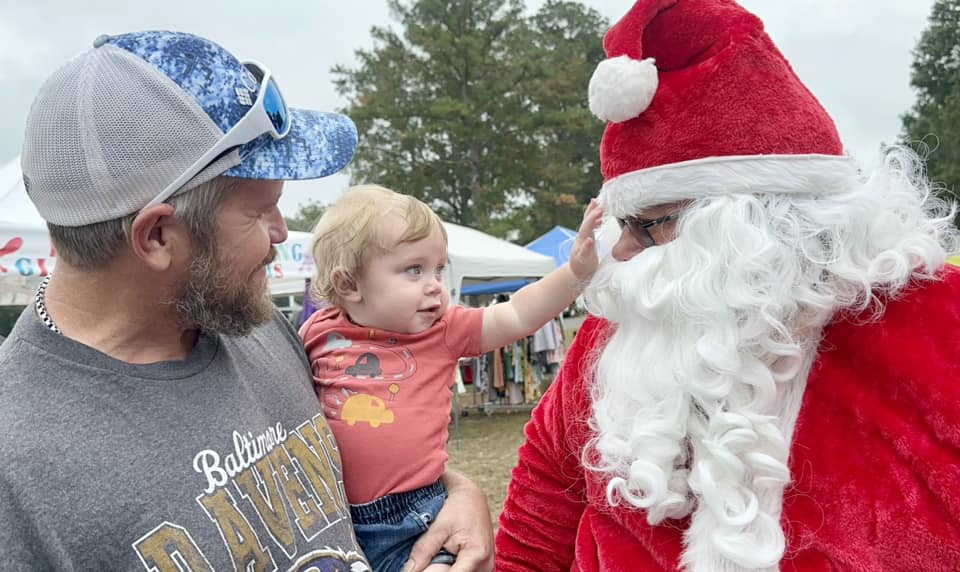 A man holding a child and wearing a santa suit.