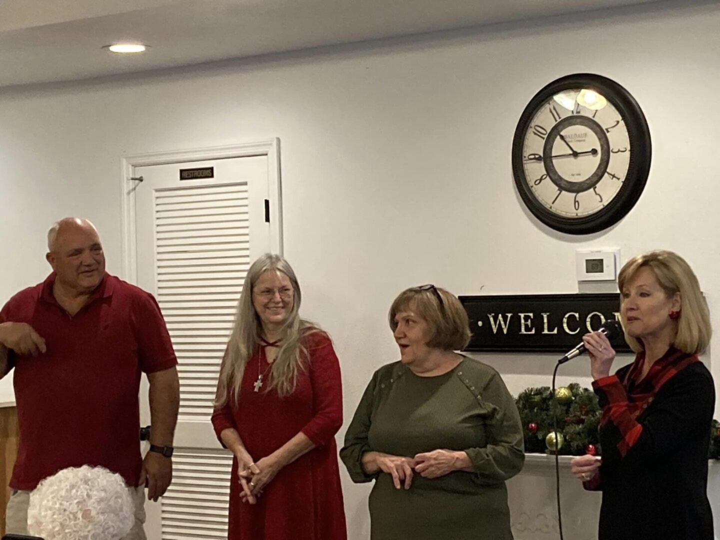 Four adults singing near welcome sign