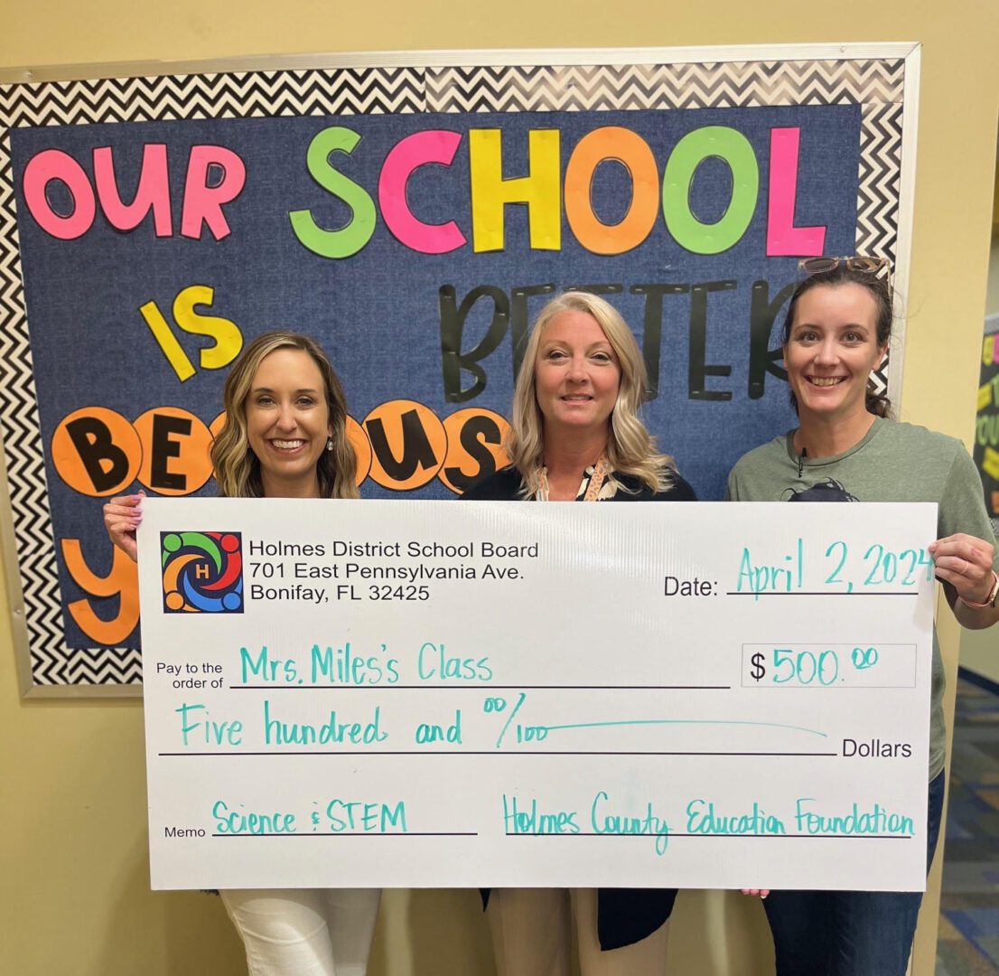 Three adults holding oversized school donation check