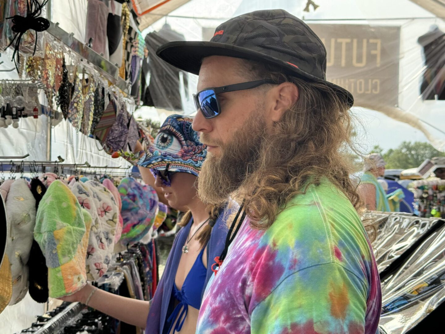Person in tie-dye shirt browsing colorful hats