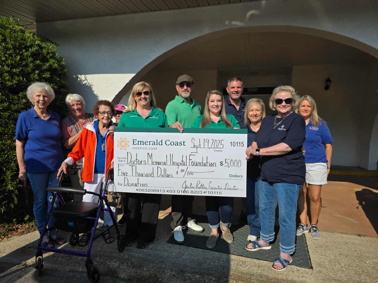 Group holding oversized charity check outdoors