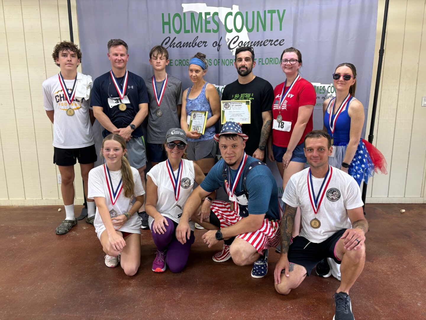 Group of medalists posing under Holmes County banner