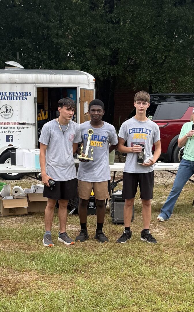 Three teenage runners holding trophy and medals
