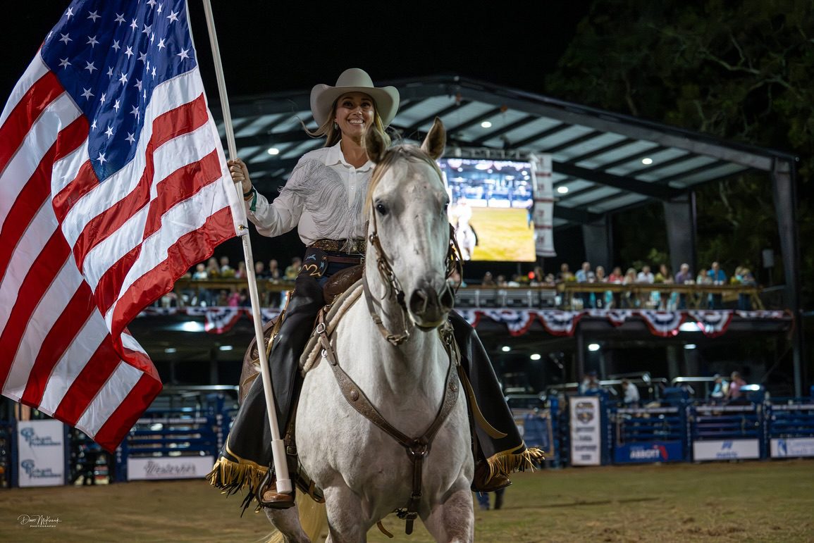 Cowgirl on white horse holding American flag
