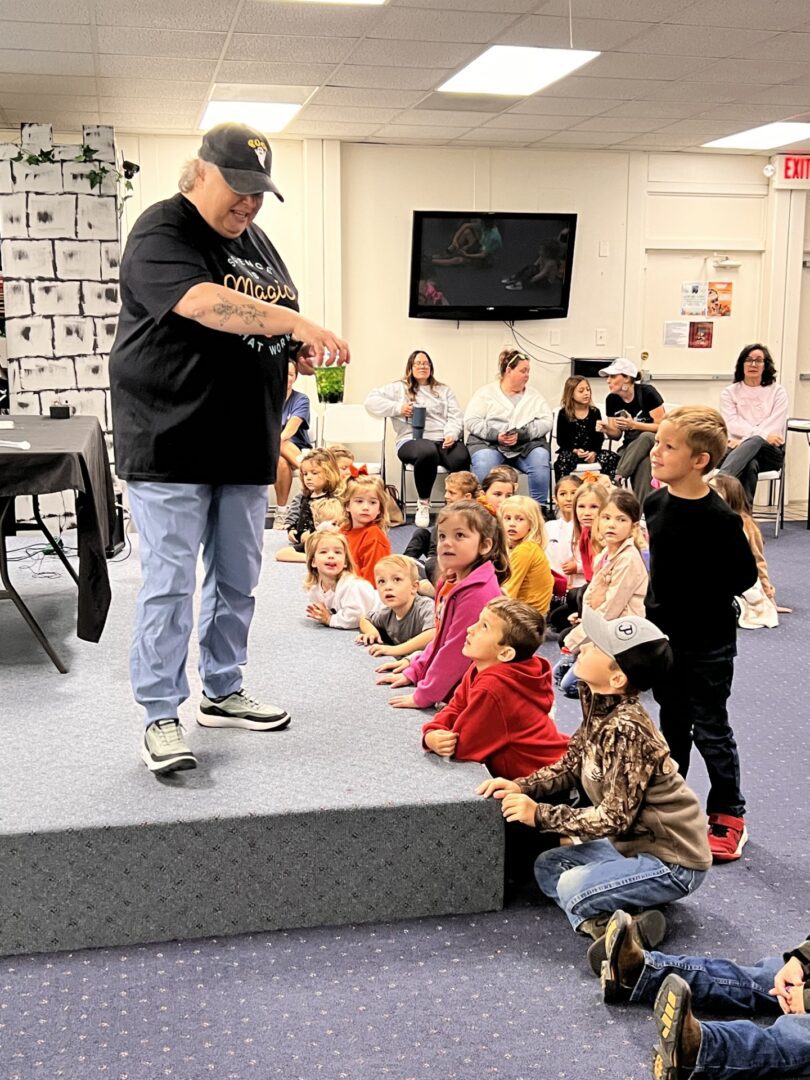 Man entertaining group of seated children indoors