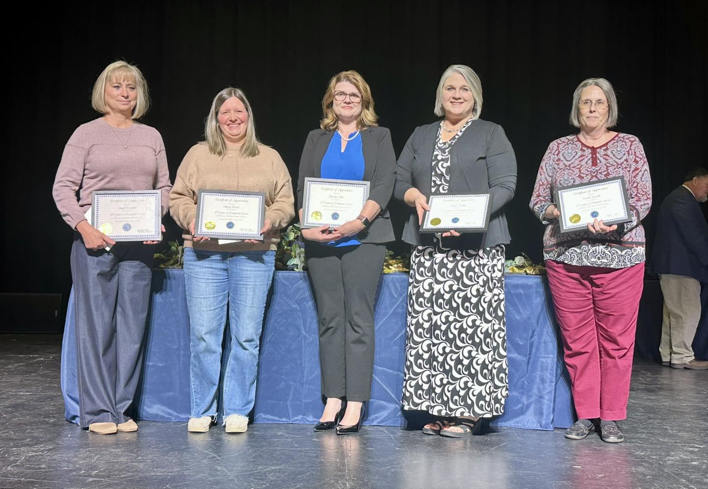 Five women on stage holding certificates