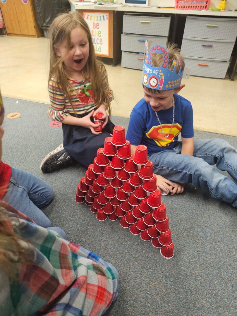 Kids stacking red plastic cups into pyramid Kids stacking red plastic cups into pyramid