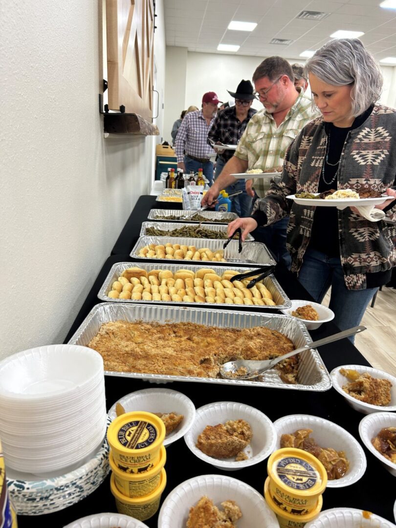 People serving themselves at buffet table People serving themselves at buffet table