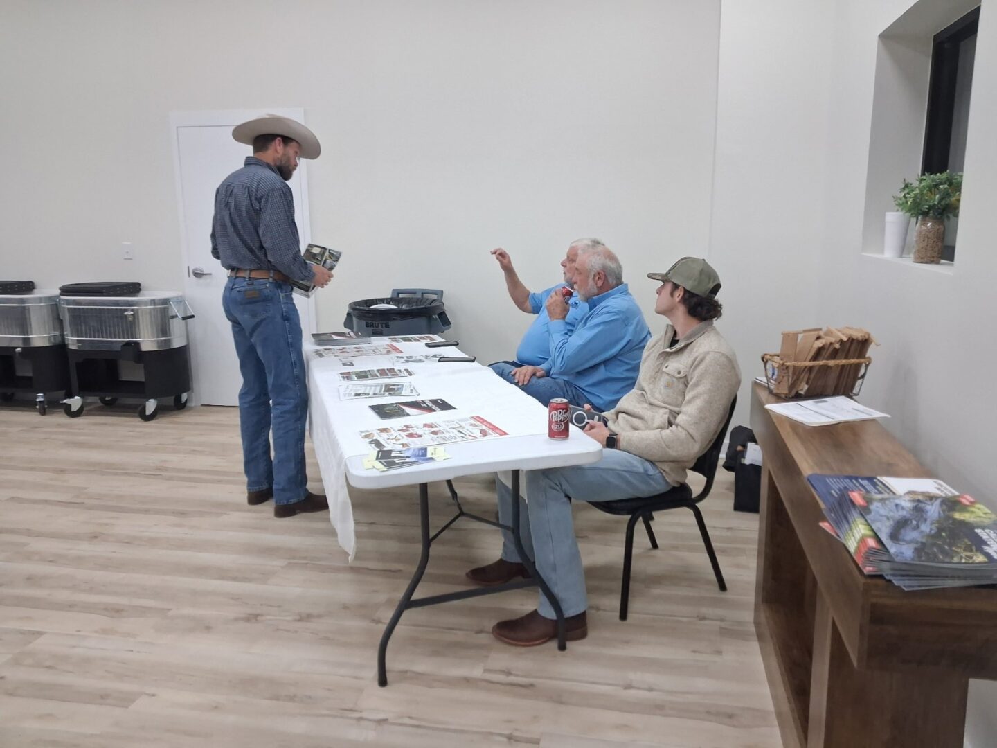 Three men at table with printed materials Three men at table with printed materials