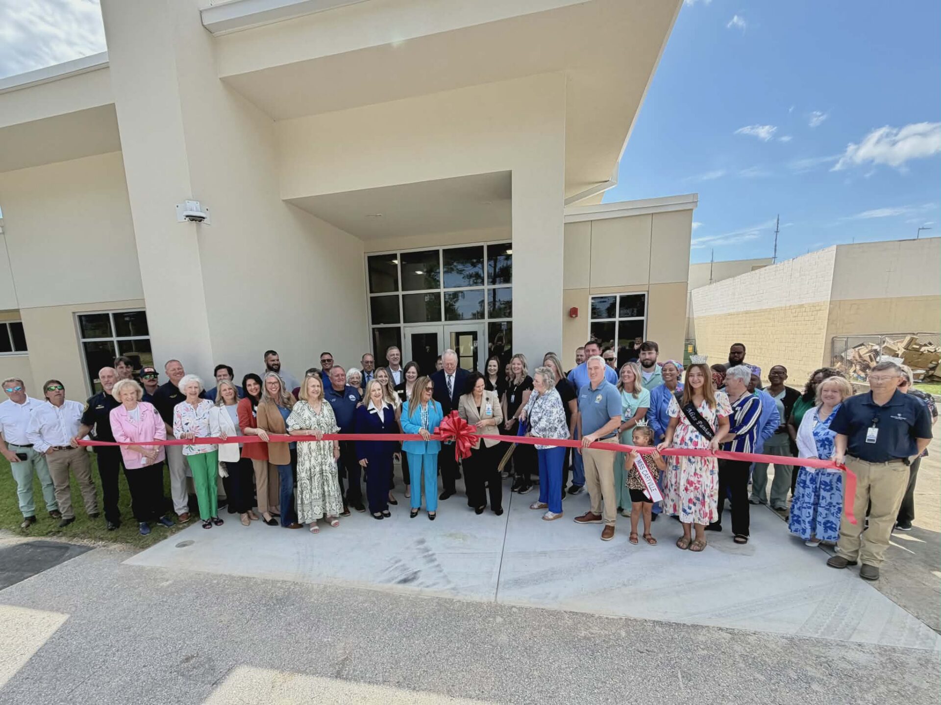 Ribbon-cutting ceremony with crowd outside building